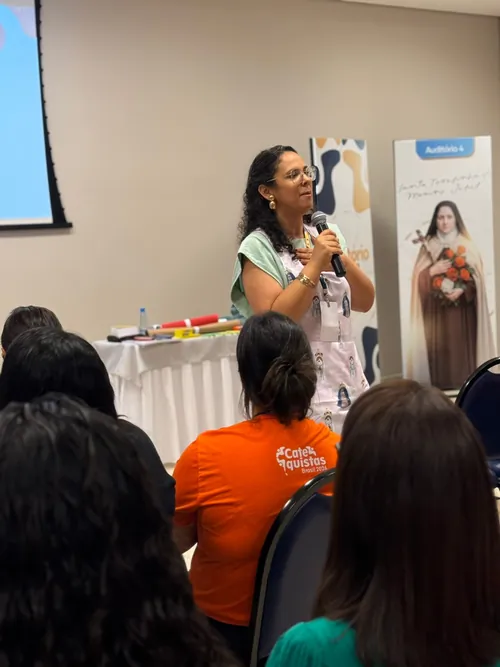 Carol Zabisky falando ao microfone para uma turma de catequistas