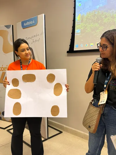 Participante apresentando ao microfone o material criado na oficina